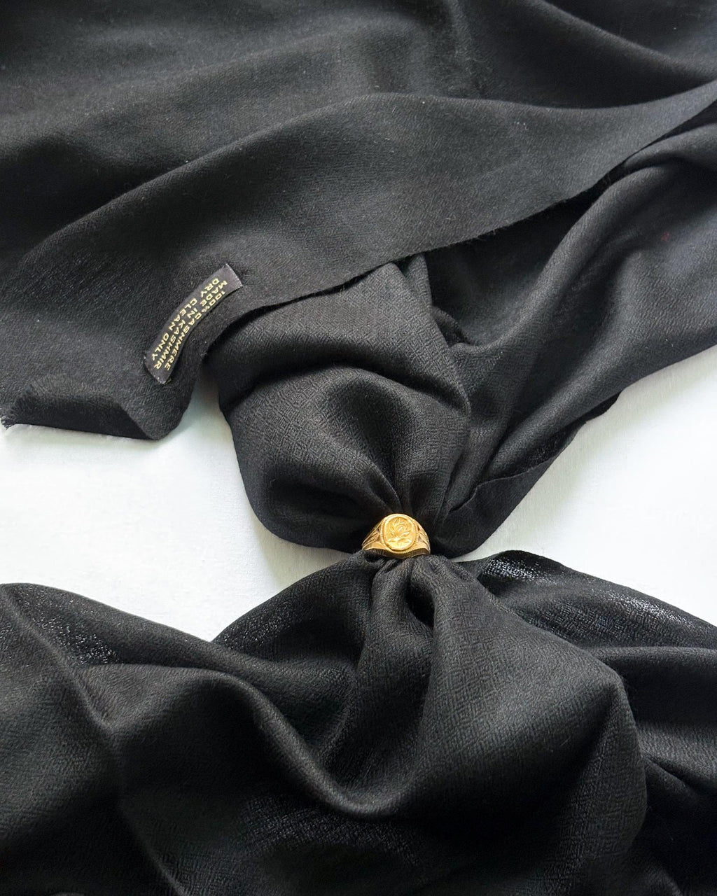 Black fabric with a gold button and tag on a white background