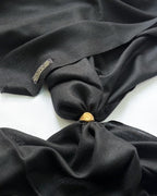 Black fabric with a gold button and tag on a white background