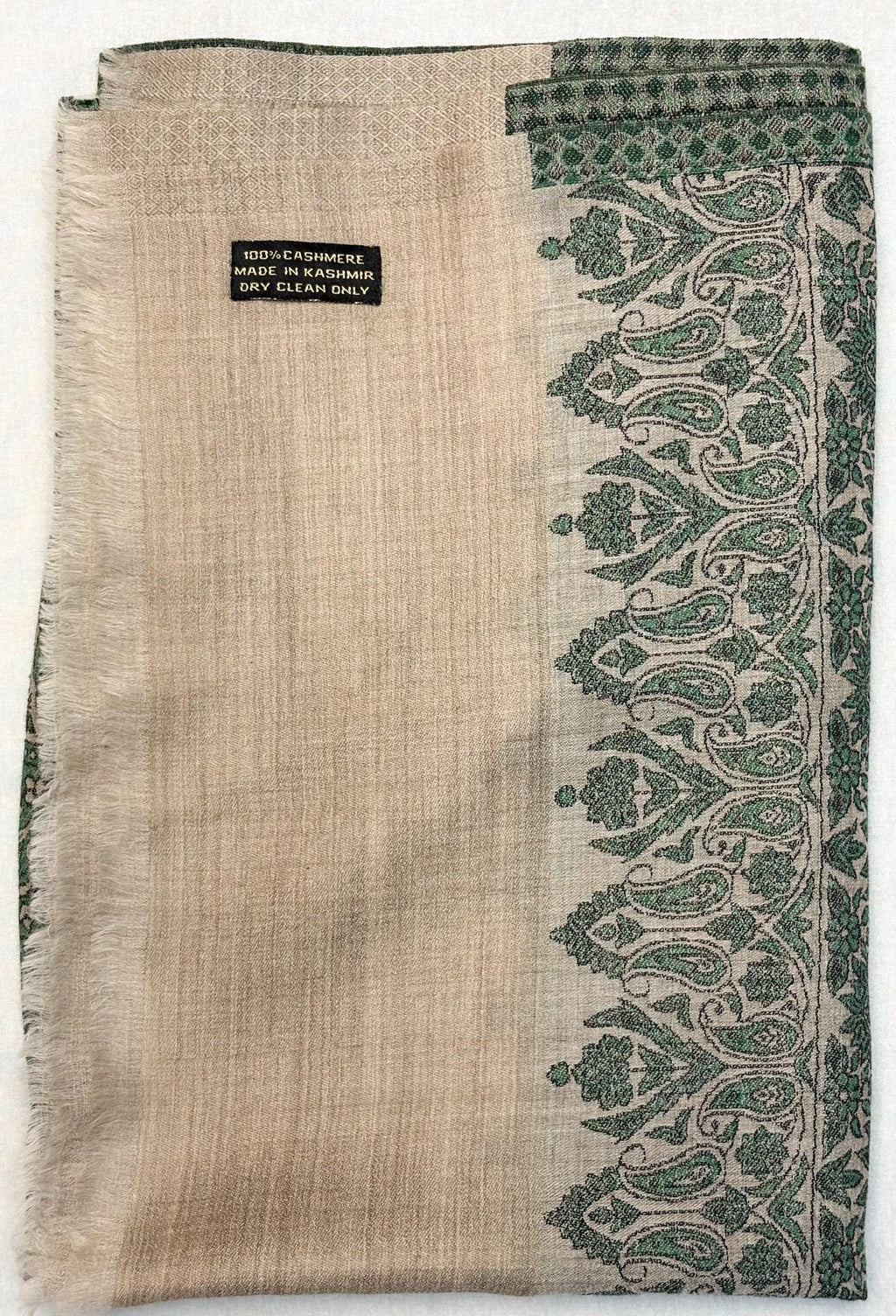 Textured fabric with green paisley pattern and visible brand label on a white background
