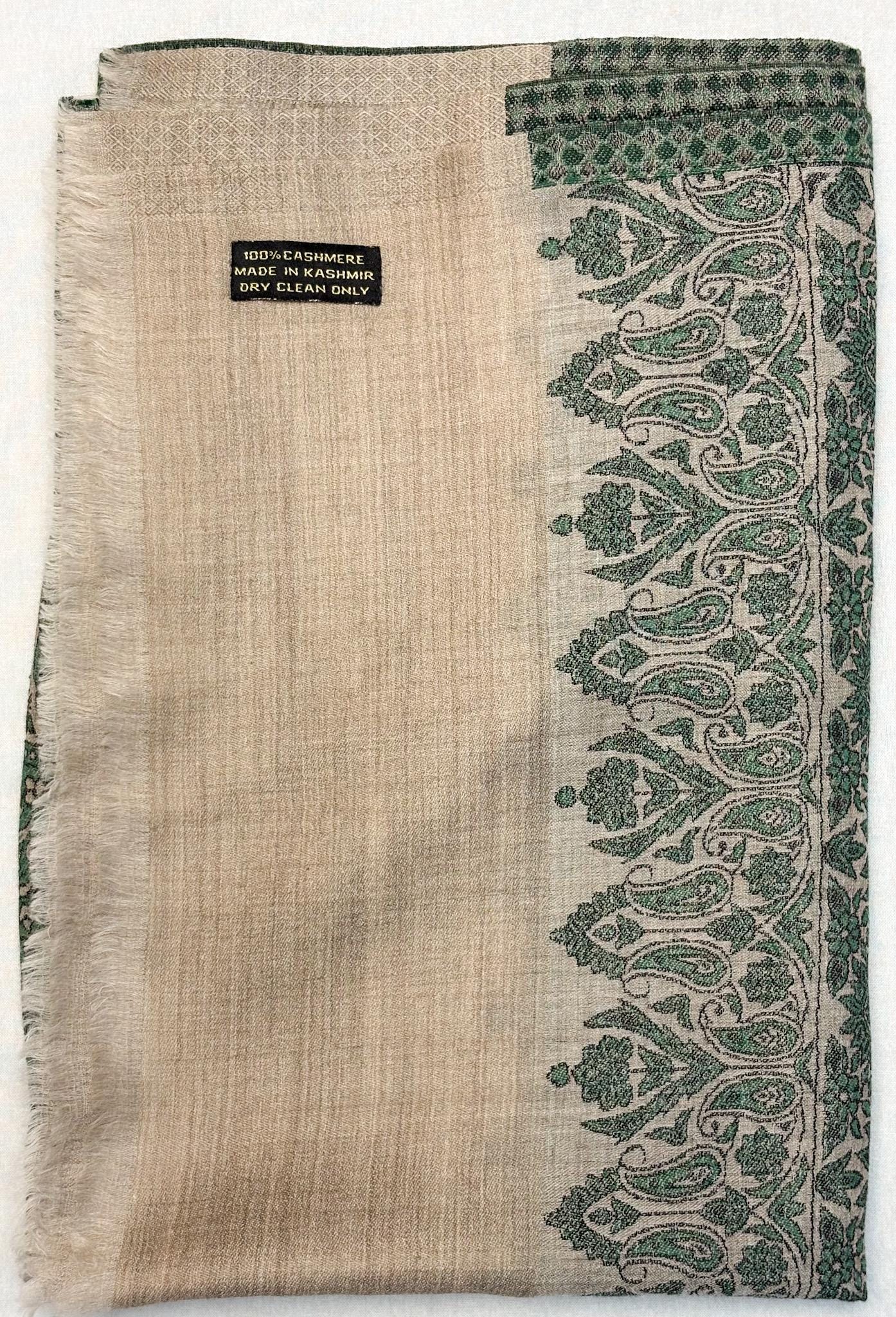 Textured fabric with green paisley pattern and visible brand label on a white background