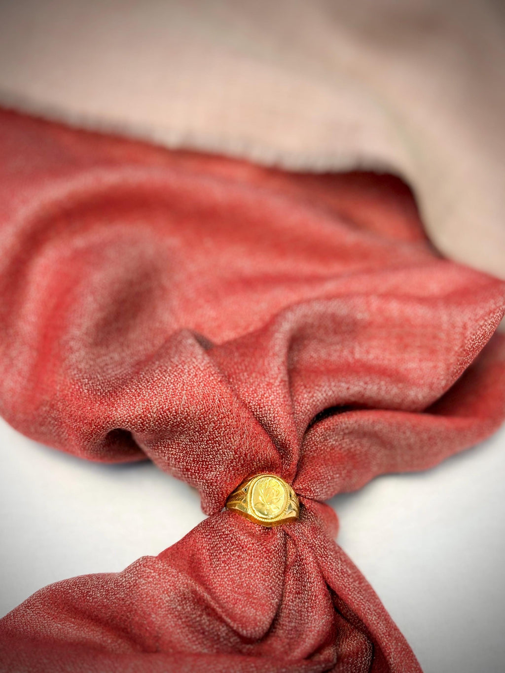 Red fabric with a gold ring on a neutral background