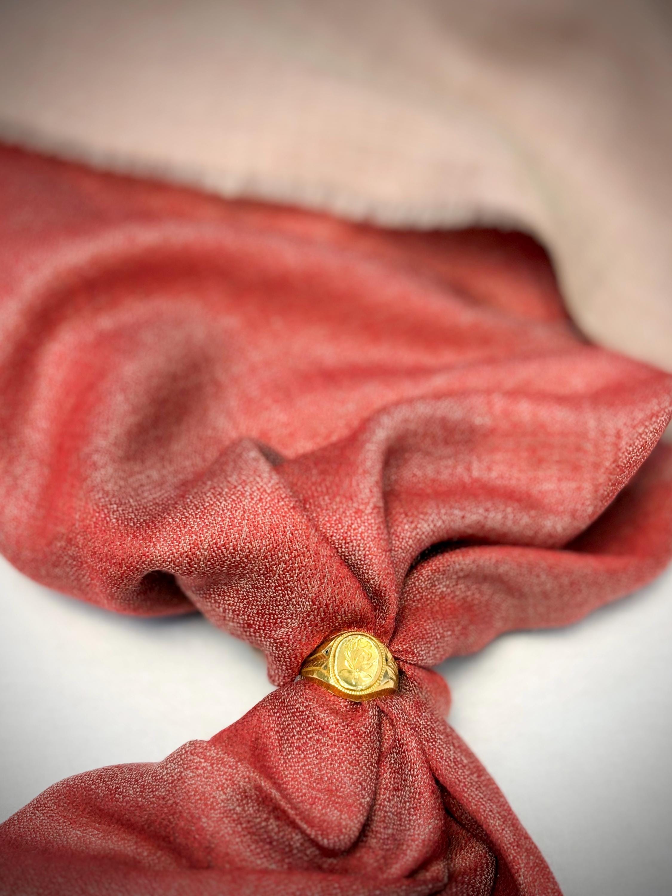 Red fabric with a gold ring on a neutral background