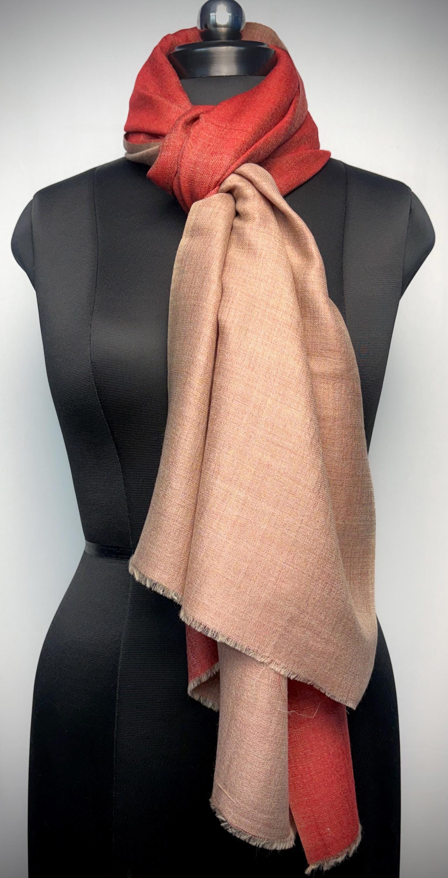 Mannequin wearing a red and beige scarf on a plain background
