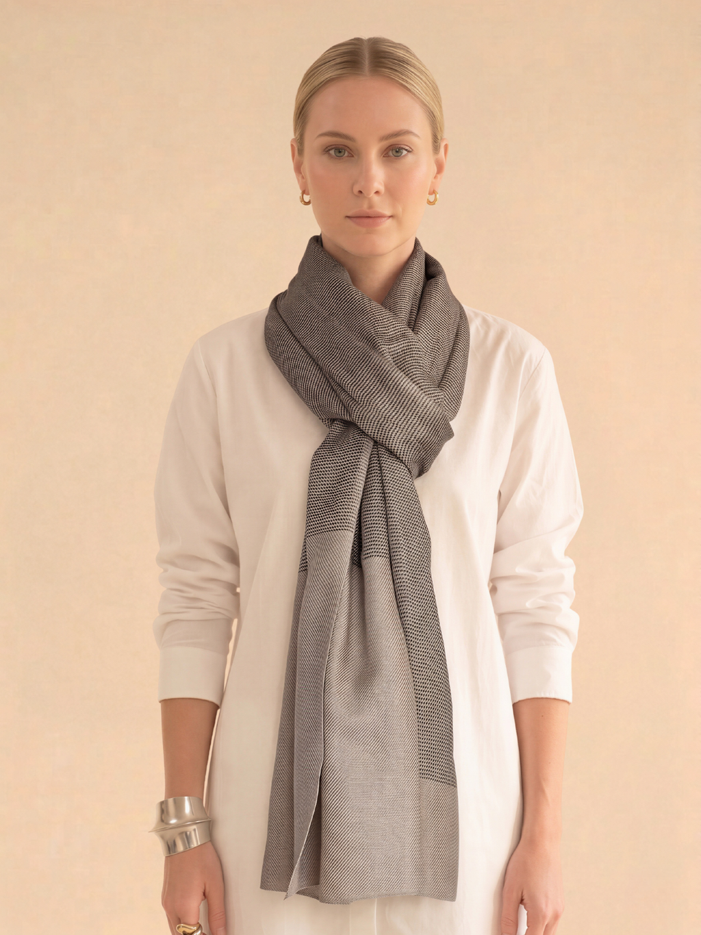 Woman wearing a gray scarf around her neck against a beige background