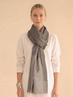 Woman wearing a gray scarf around her neck against a beige background