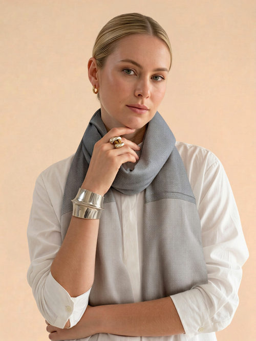 Woman wearing a gray scarf and silver bracelet against a beige background