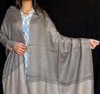 Person wearing a gray kimono-style garment against a black background