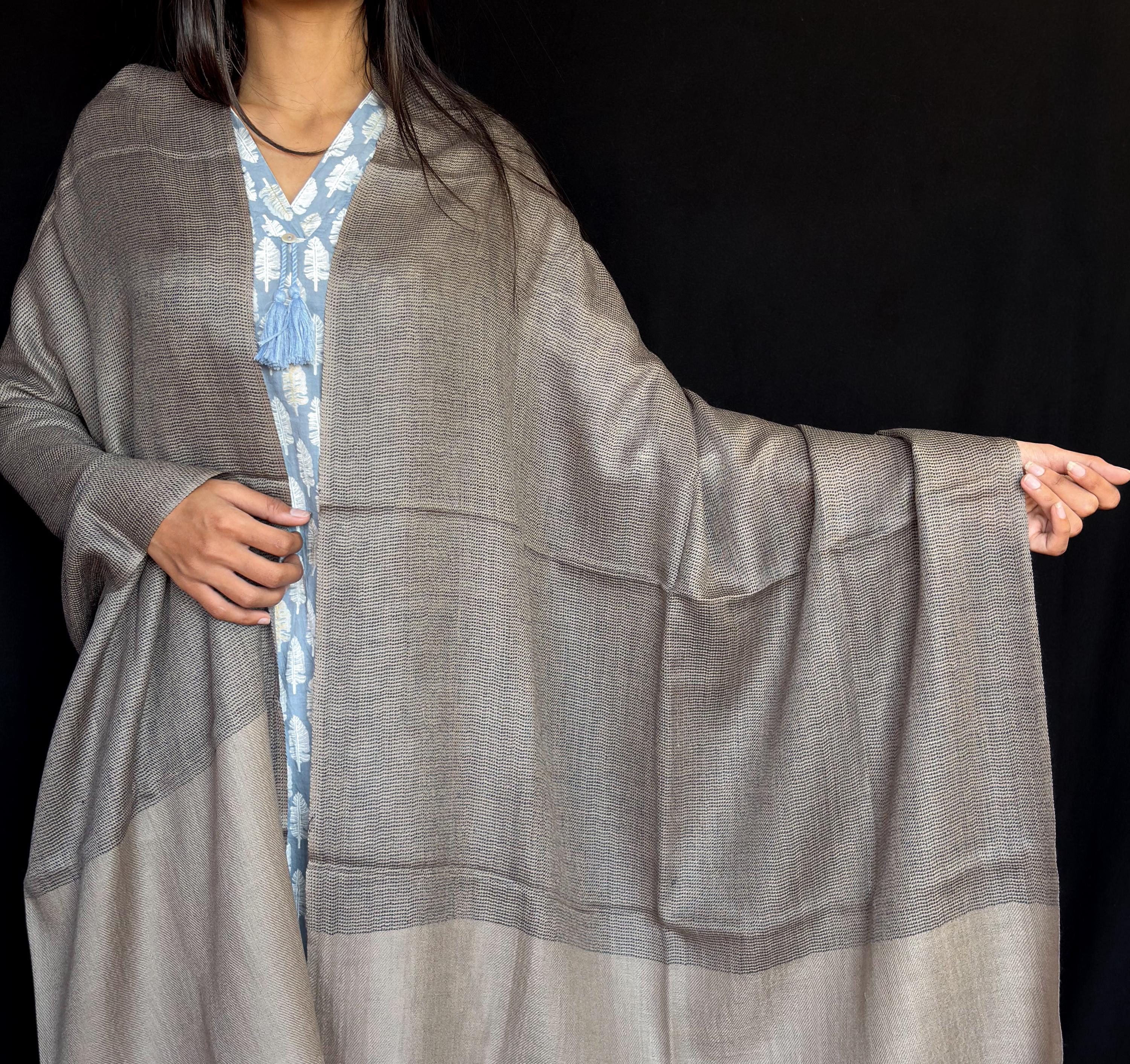 Person wearing a gray kimono-style garment against a black background