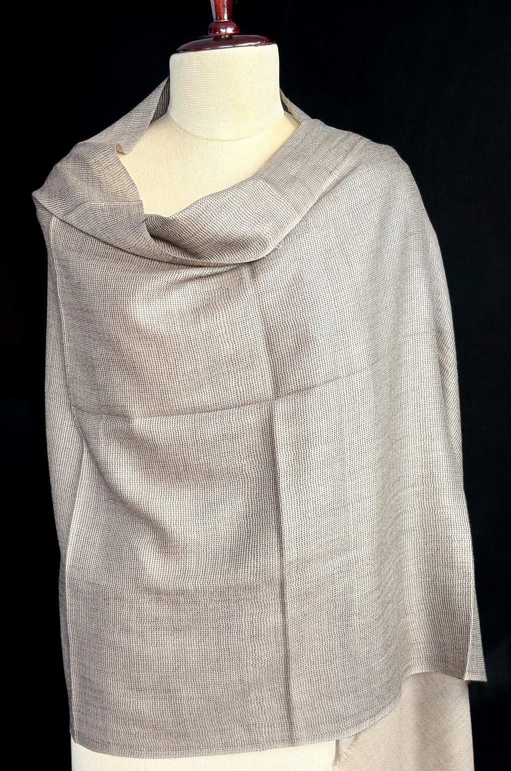 Gray scarf on a mannequin against a black background