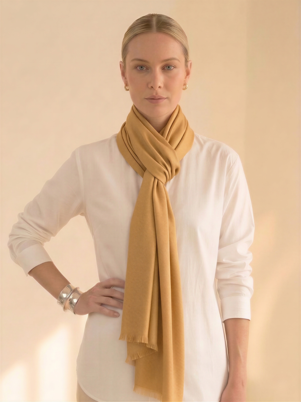 Woman wearing a mustard yellow scarf around her neck against a beige background