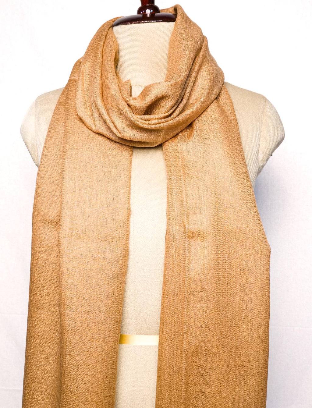 Beige scarf draped over a mannequin on a white background
