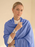 Woman wearing a blue scarf and jewelry against a beige background