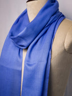 Blue scarf draped over a mannequin on a plain background