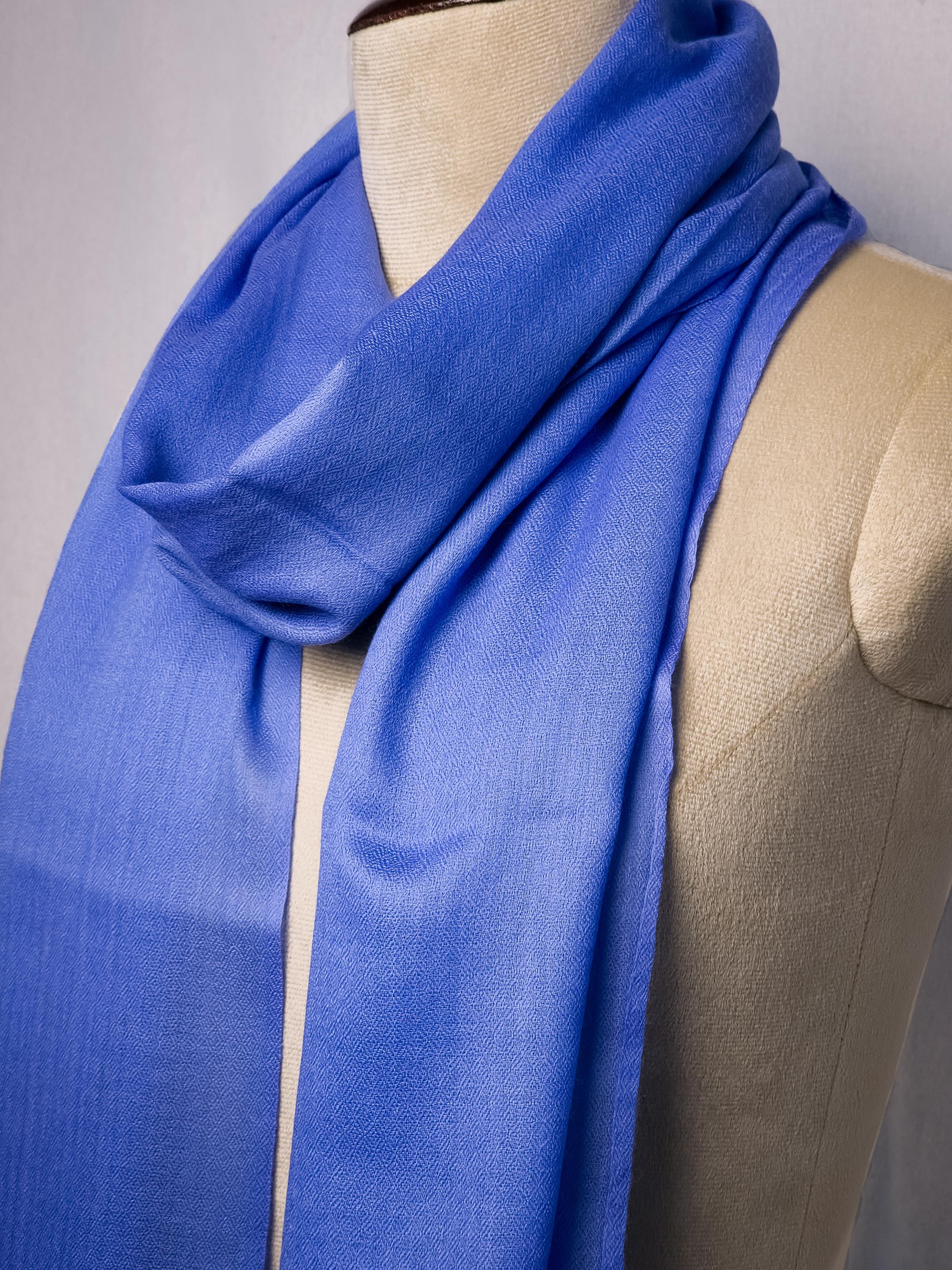 Blue scarf draped over a mannequin on a plain background