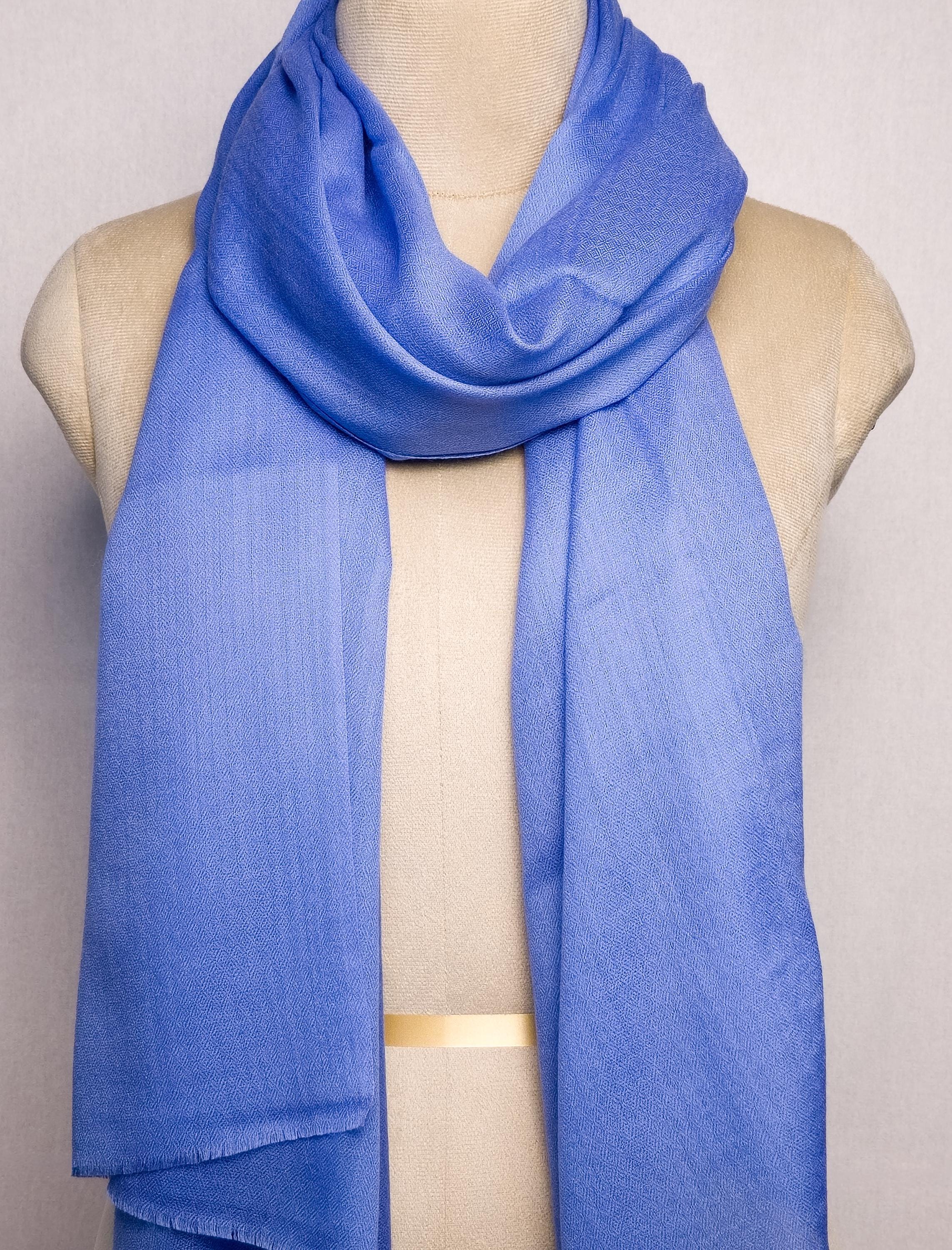 Blue scarf draped over a mannequin on a plain background