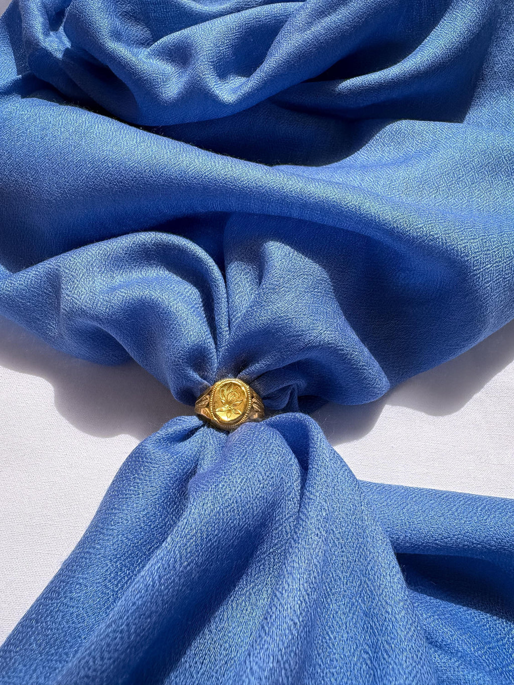 Gold ring with a yellow gemstone on a blue fabric background