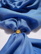 Gold ring with a yellow gemstone on a blue fabric background