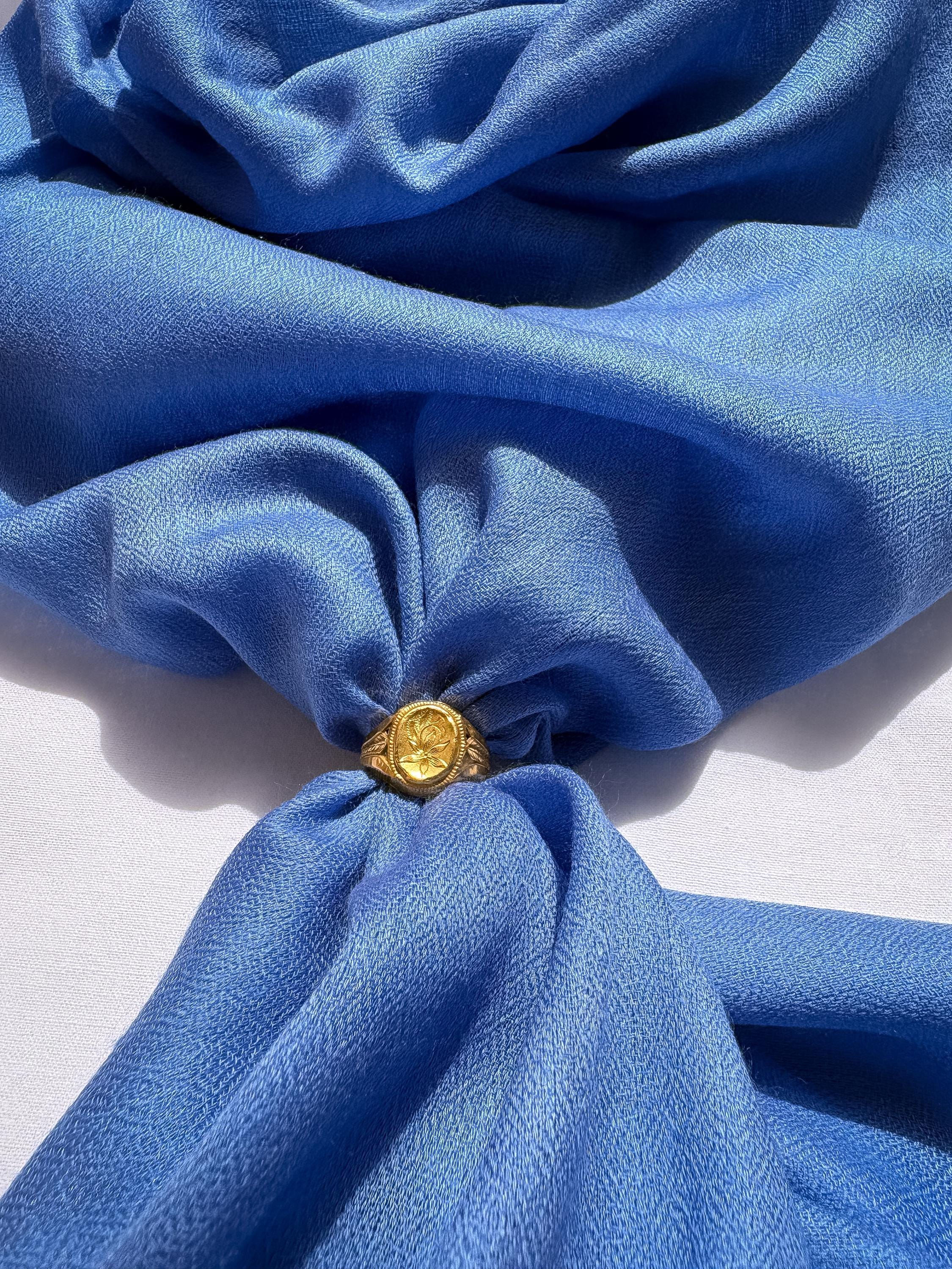 Gold ring with a yellow gemstone on a blue fabric background