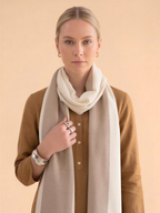 Woman wearing a beige scarf and brown shirt against a beige background