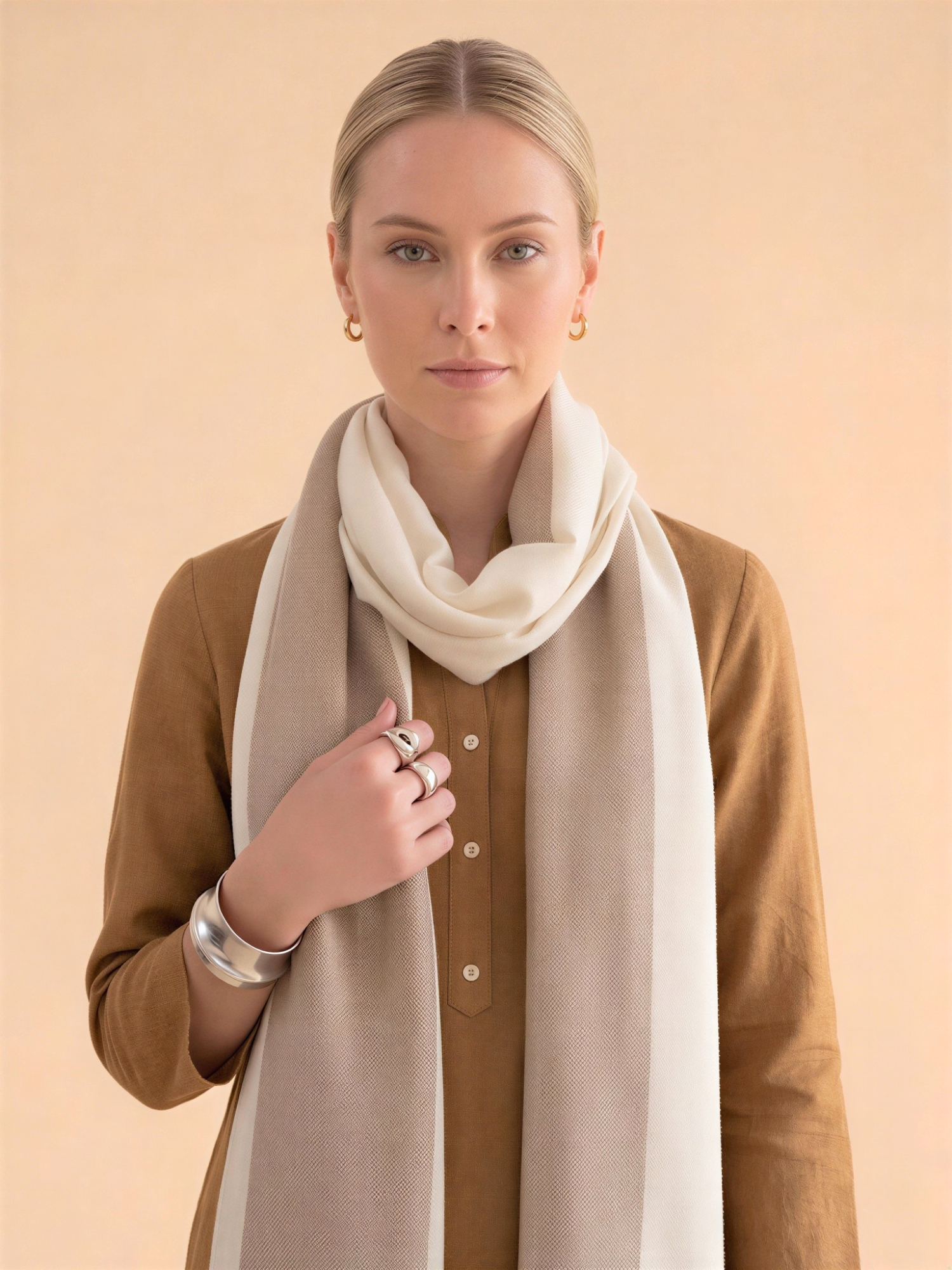 Woman wearing a beige scarf and brown shirt against a beige background