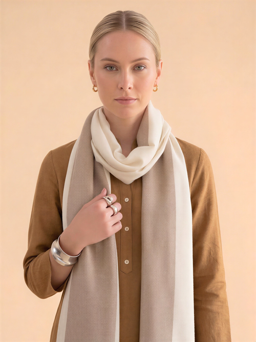 Woman wearing a beige scarf and brown shirt against a beige background