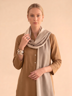 Woman wearing a long beige scarf with a beige background