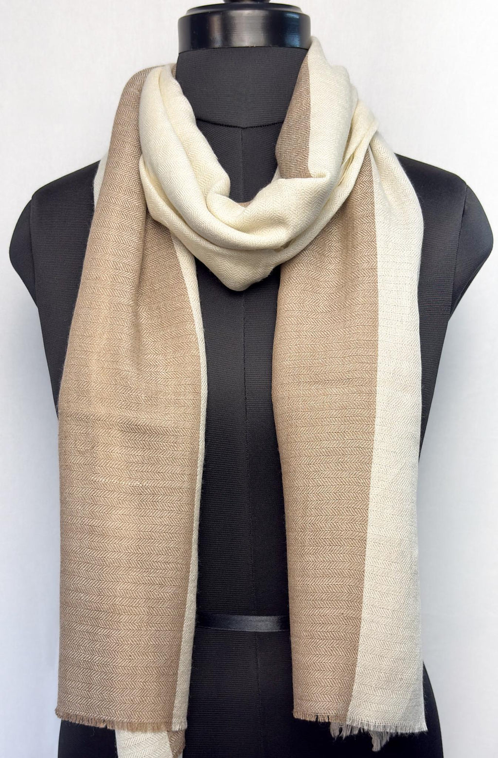 Mannequin wearing a beige and white scarf on a plain background