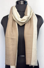 Mannequin wearing a beige and white scarf on a plain background