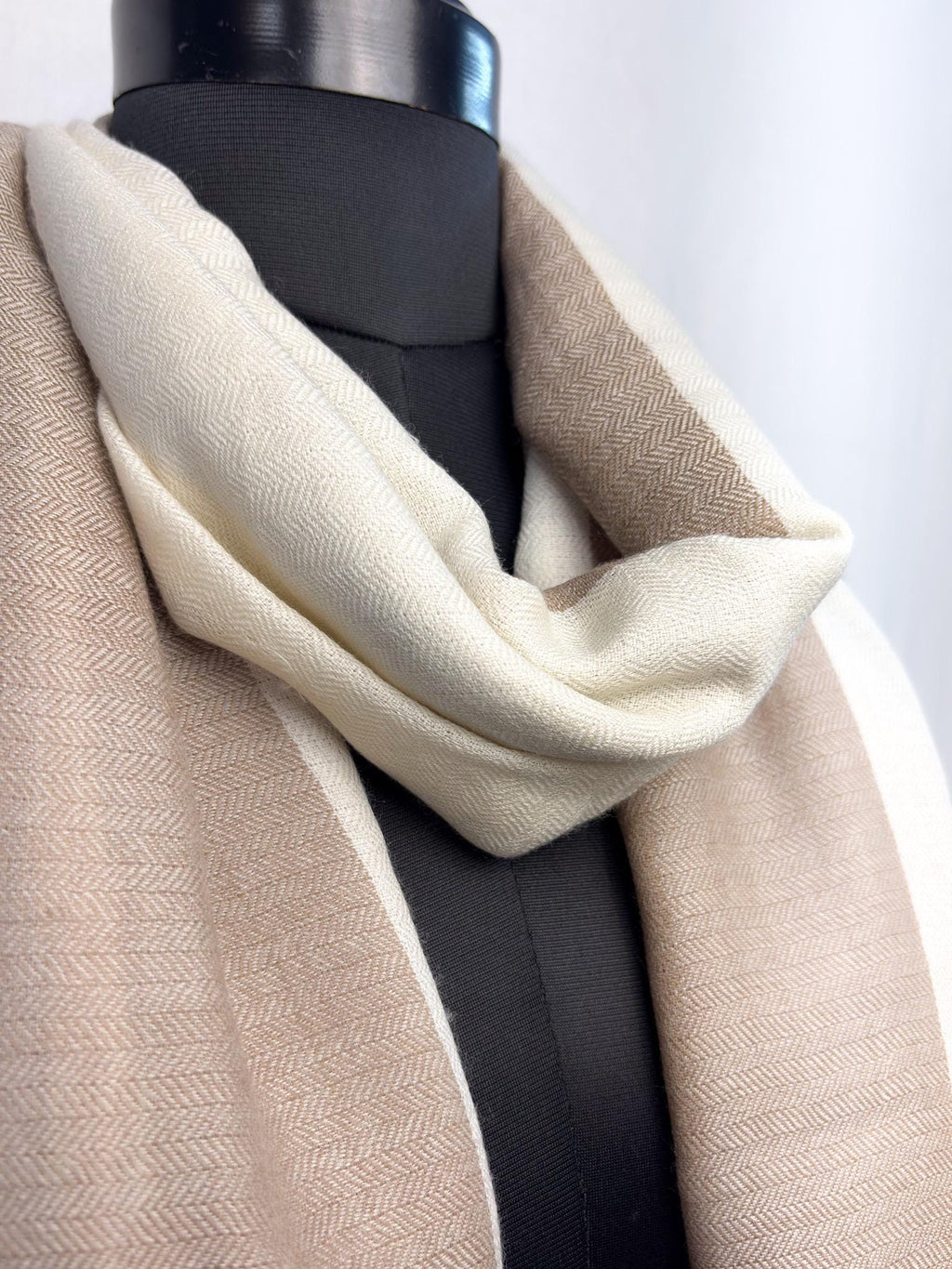 Mannequin wearing a beige and white scarf with a plain background