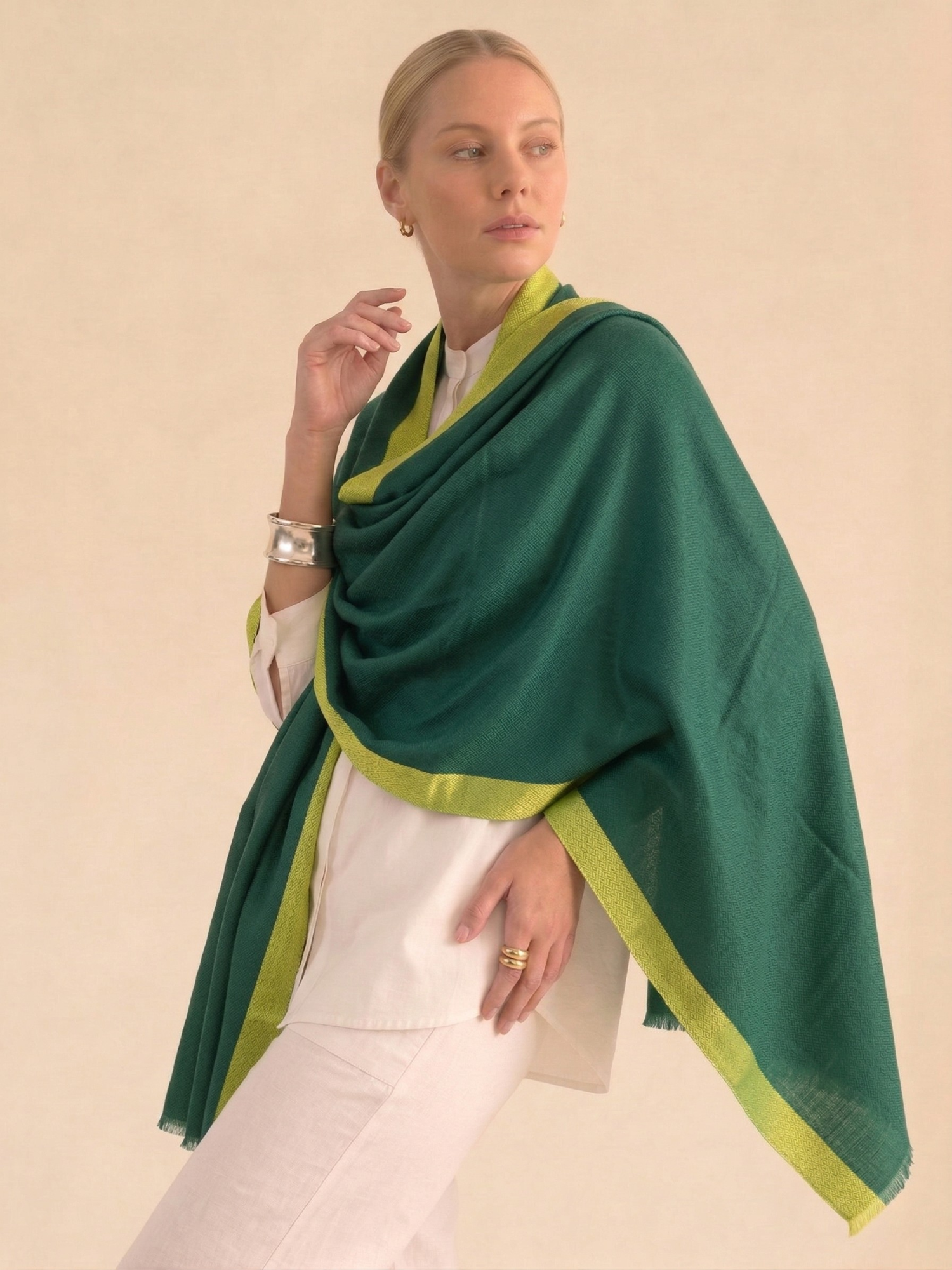 Woman wearing a green and yellow shawl against a beige background