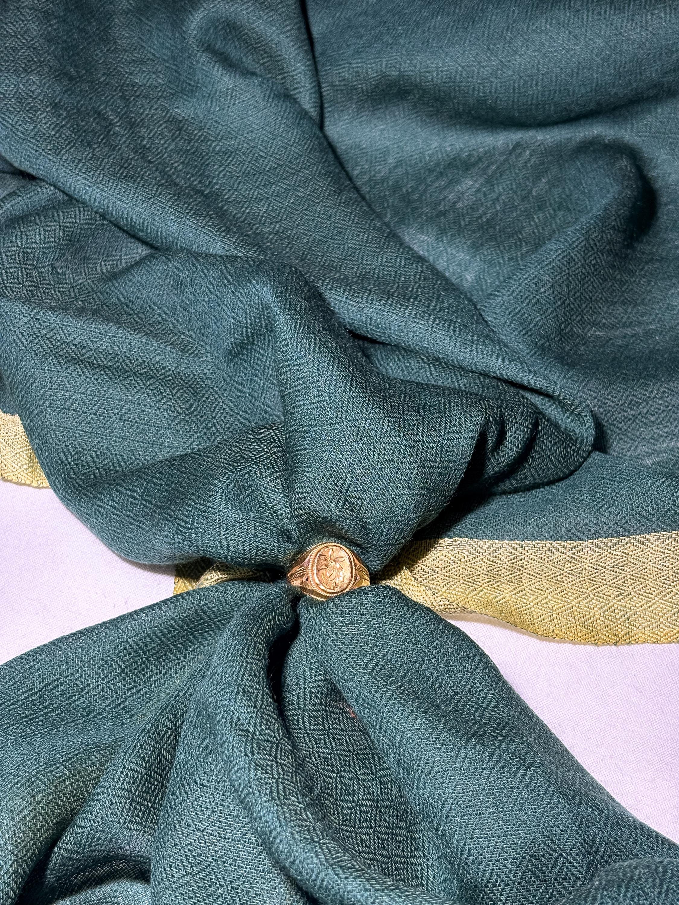 Teal fabric with a gold button on a white background