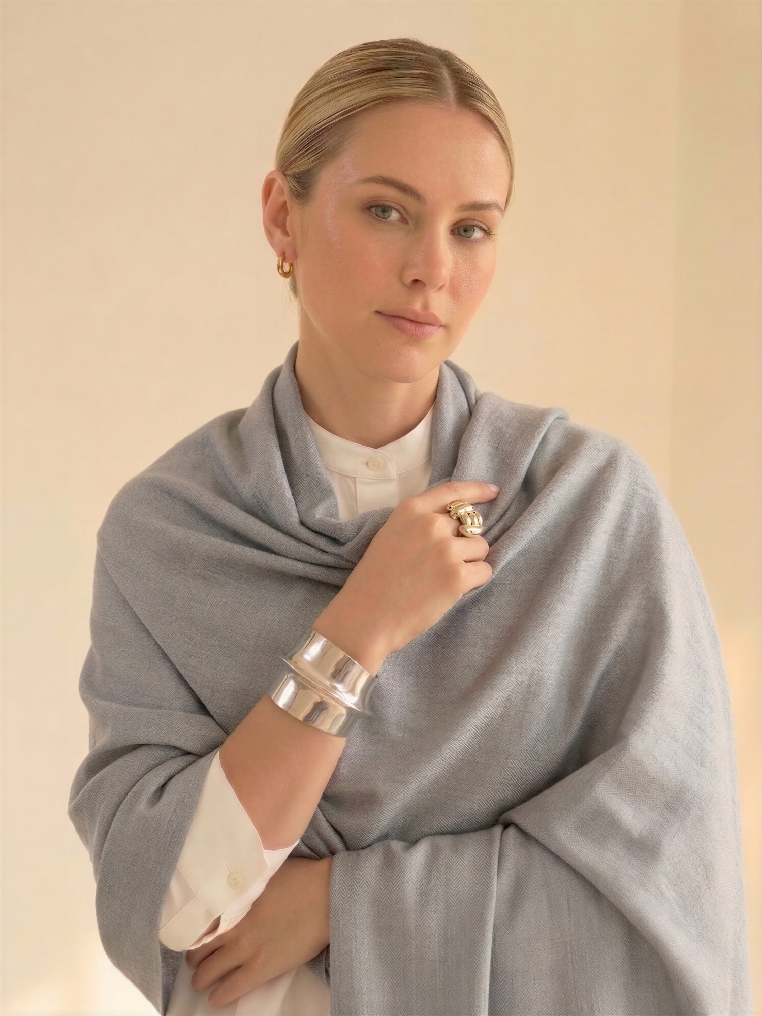 Woman wearing a gray shawl against a beige background