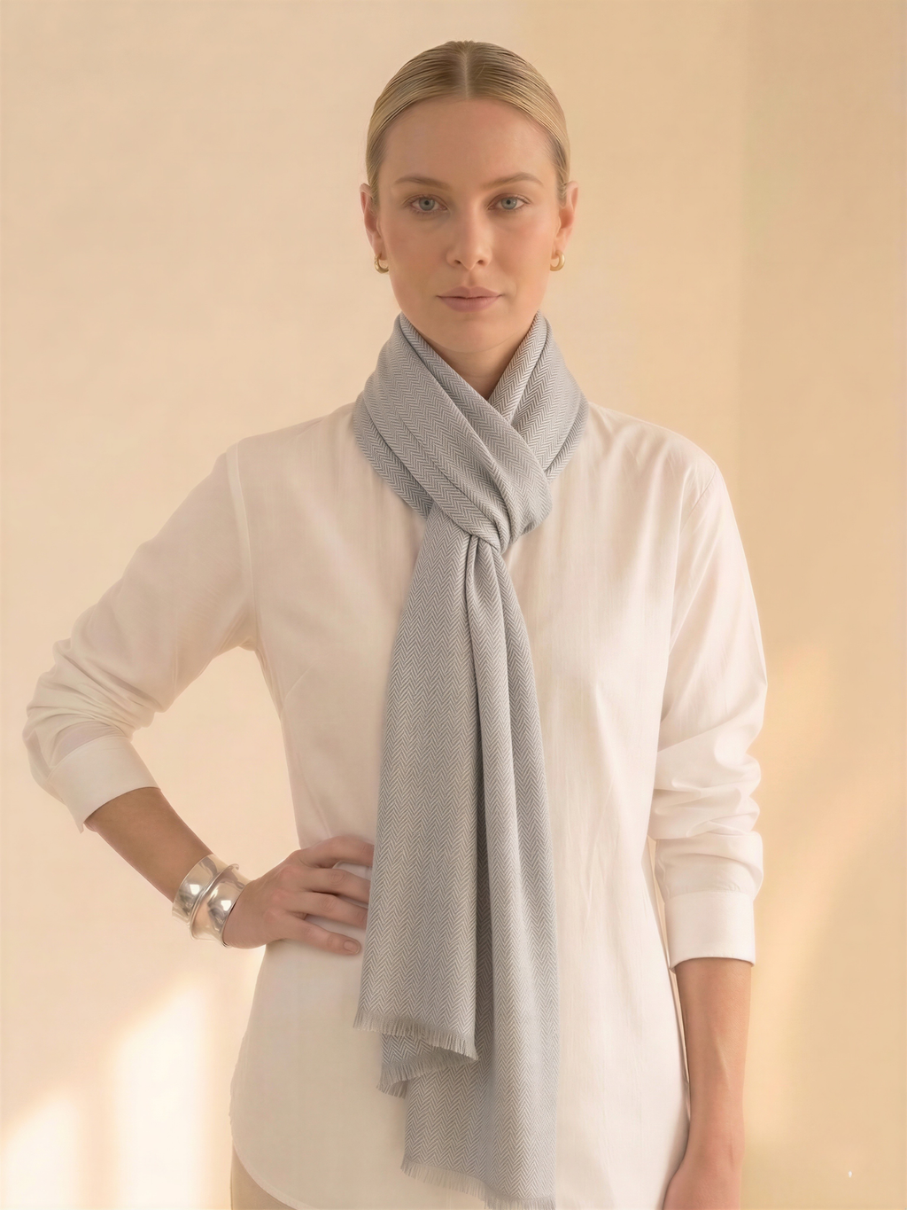 Woman wearing a light gray scarf around her neck against a beige background