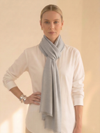 Woman wearing a light gray scarf around her neck against a beige background