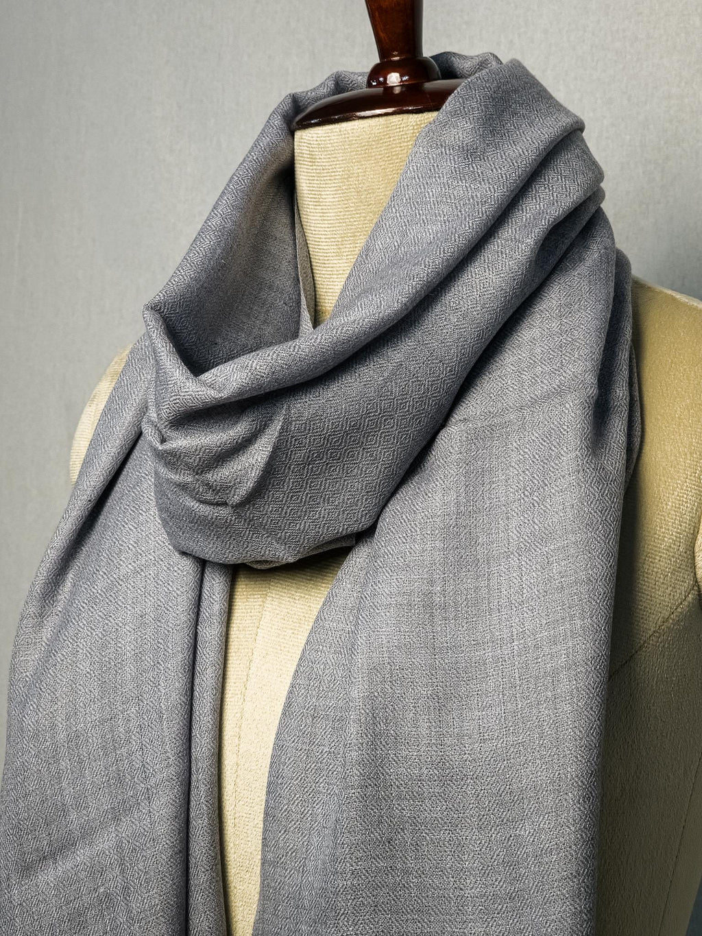 Gray scarf draped over a mannequin on a gray background