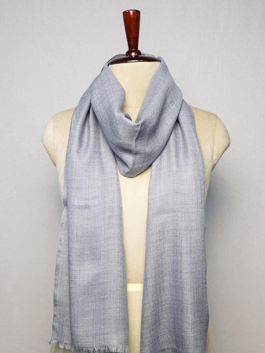 Gray scarf on a mannequin against a plain background