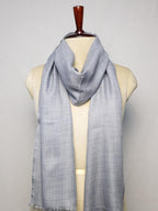 Gray scarf on a mannequin against a plain background