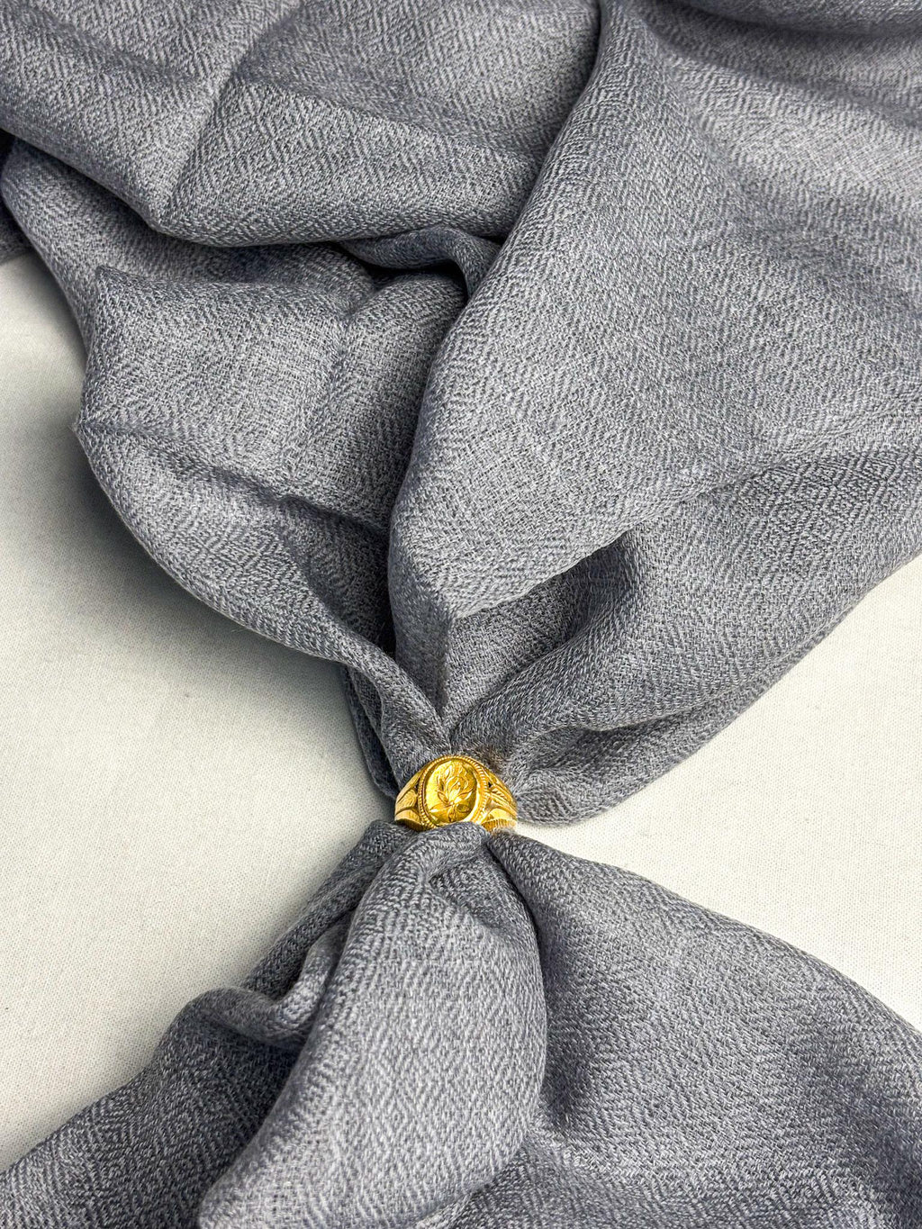 Gray fabric with a gold tie knot on a light background