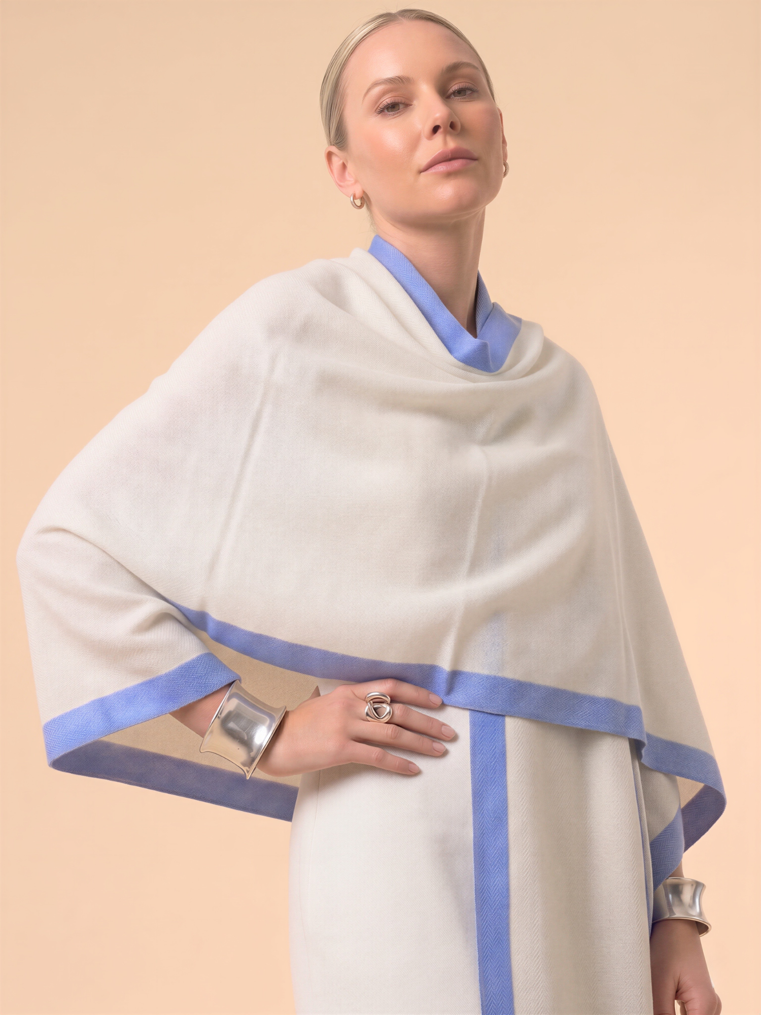 Woman wearing a white shawl with blue trim on a beige background