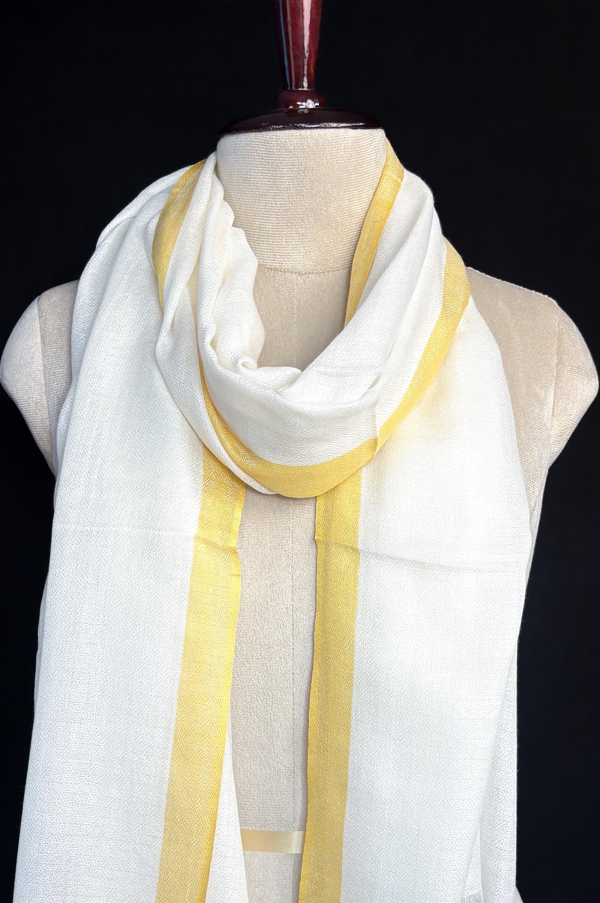 White scarf with yellow stripes draped over a mannequin against a black background