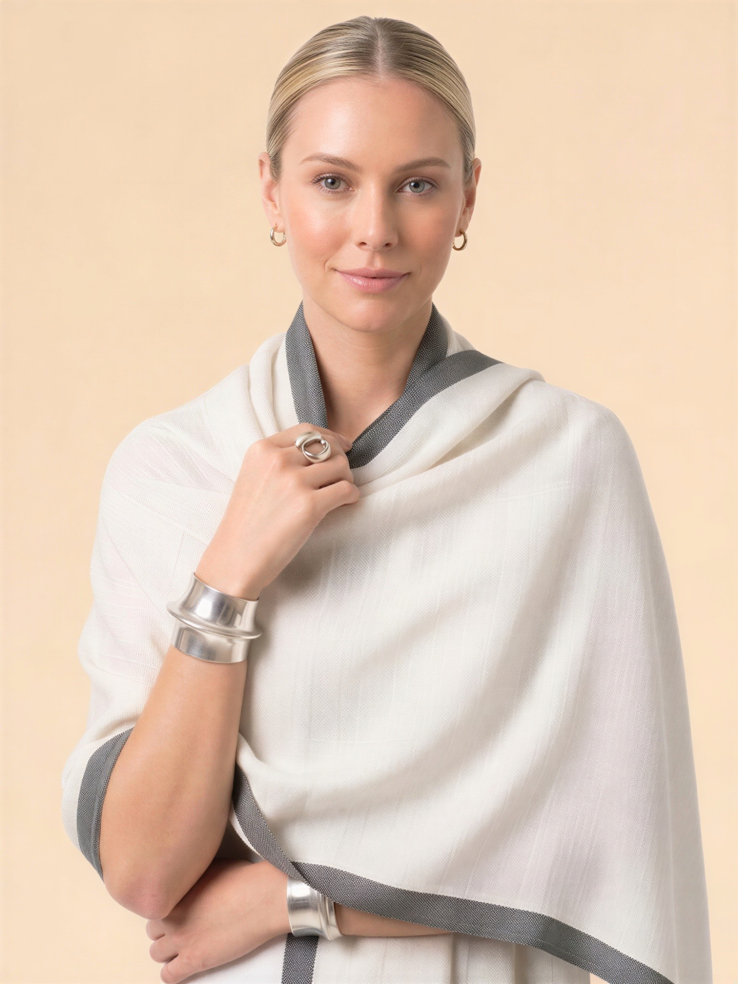 Woman wearing a white shawl with gray trim on a beige background