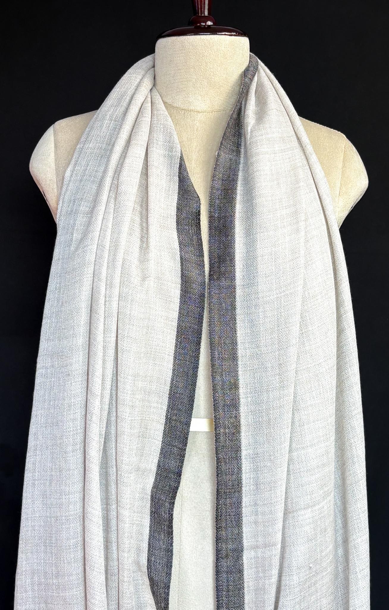 Mannequin wearing a white scarf with a blue stripe on a black background
