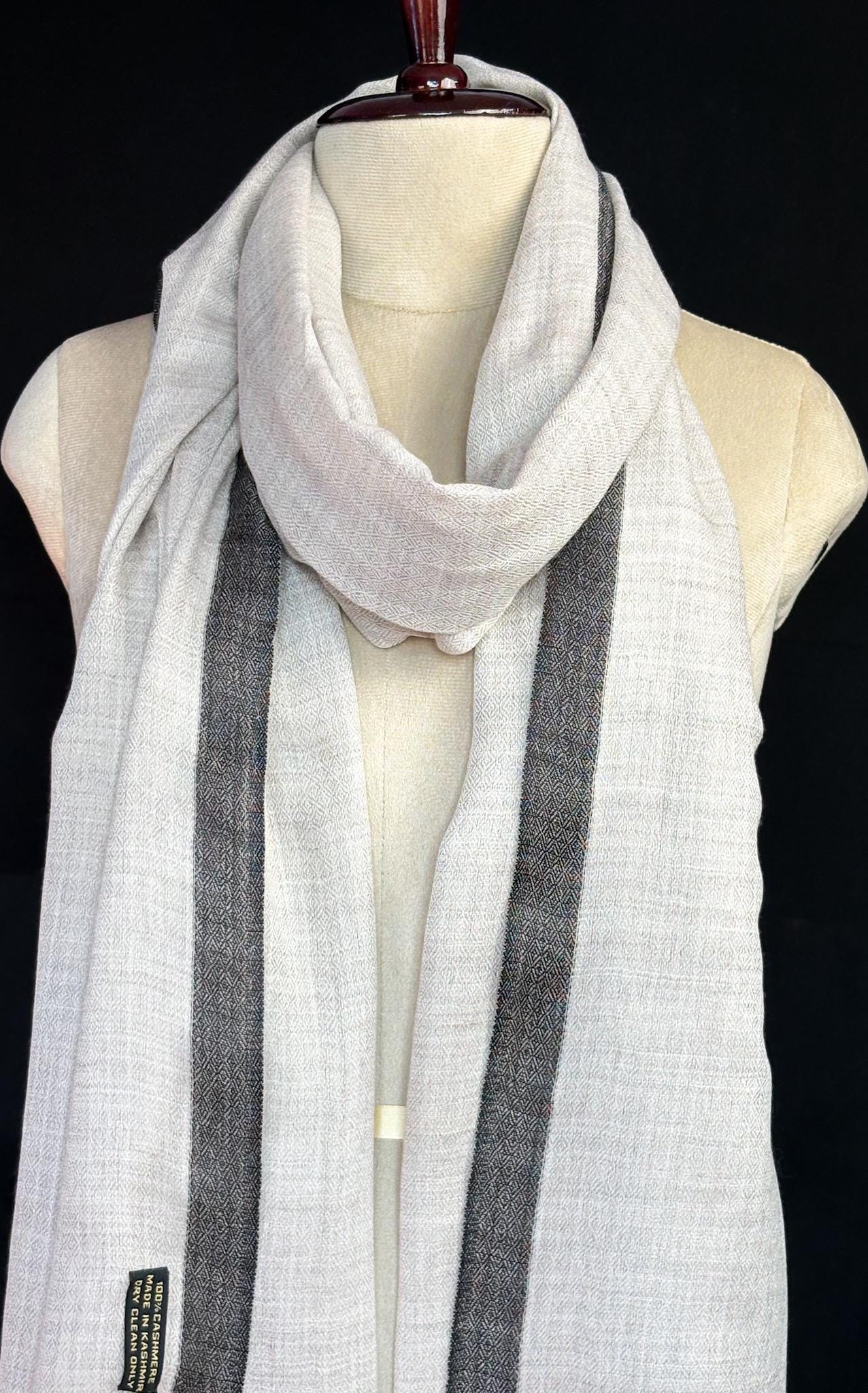 White scarf with black stripes on a mannequin against a black background