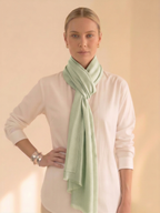 Woman wearing a light green scarf around her neck against a beige background