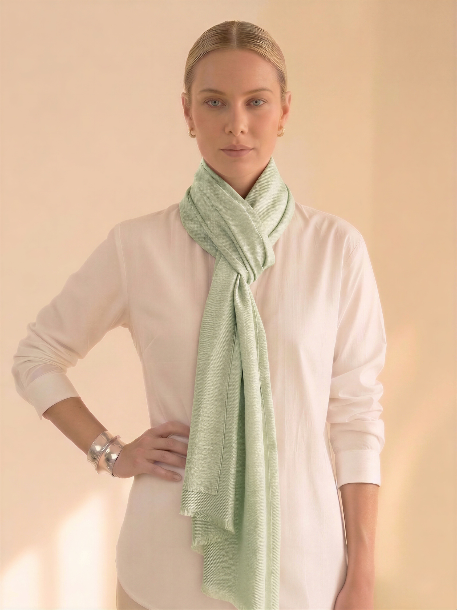 Woman wearing a light green scarf around her neck against a beige background