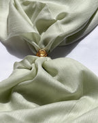 Gold ring on a light green fabric background