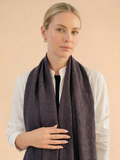 Woman wearing a dark purple scarf against a beige background