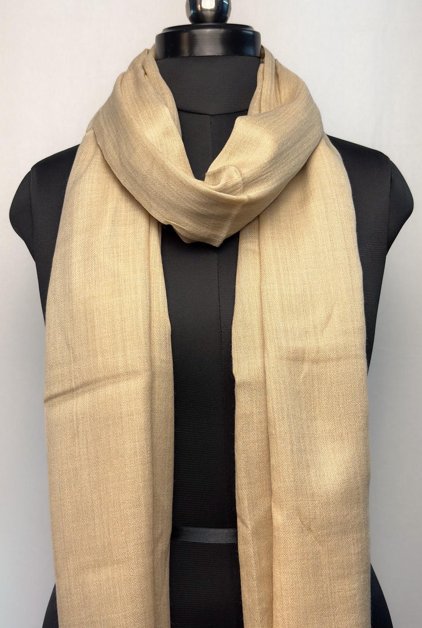 Beige scarf draped over a black mannequin against a white background