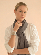 Woman wearing a gray scarf with a plain background