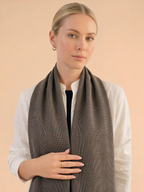 Woman wearing a brown checkered scarf against a beige background